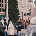 People on Reno City Plaza watching a performer sing